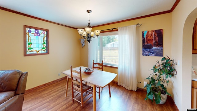 dining space featuring wood-type flooring, crown molding, and a chandelier