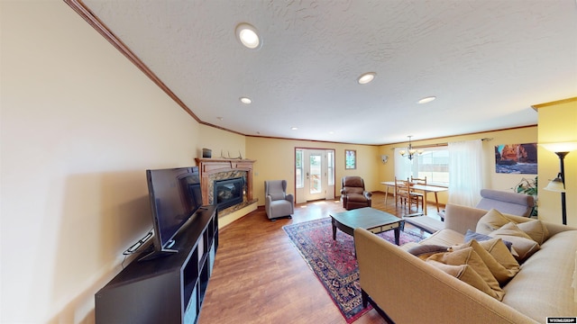 living room with hardwood / wood-style flooring, a healthy amount of sunlight, crown molding, and a textured ceiling