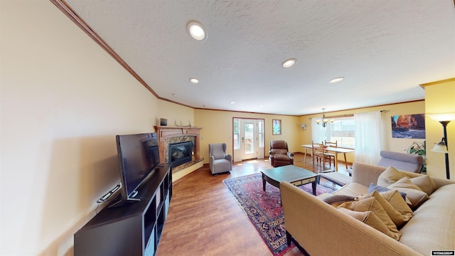 living room featuring hardwood / wood-style flooring, a textured ceiling, a notable chandelier, and ornamental molding