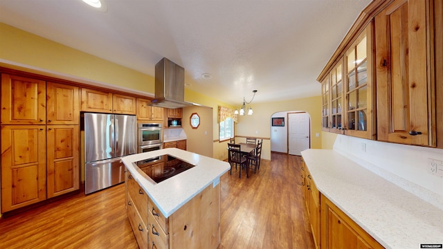 kitchen with light hardwood / wood-style flooring, decorative light fixtures, island exhaust hood, a kitchen island, and stainless steel appliances