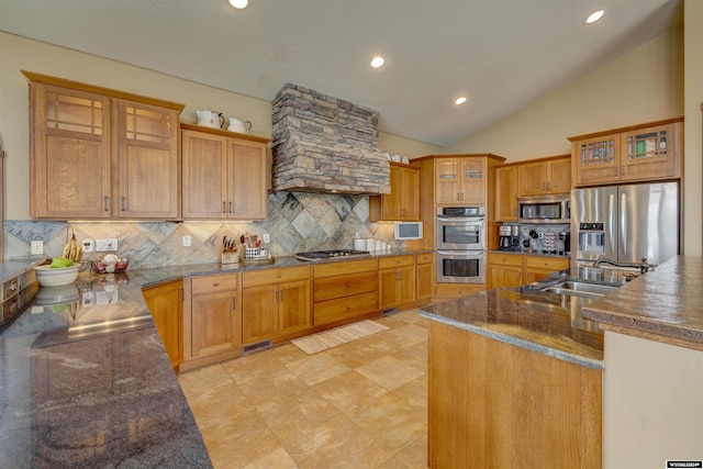 kitchen with a sink, appliances with stainless steel finishes, backsplash, and glass insert cabinets