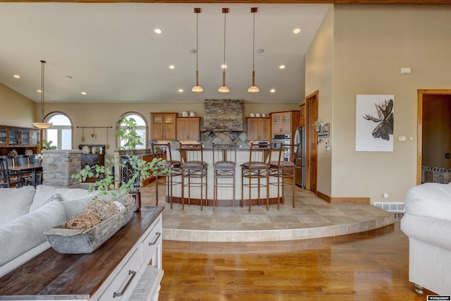 living area featuring high vaulted ceiling, light wood-type flooring, visible vents, and recessed lighting