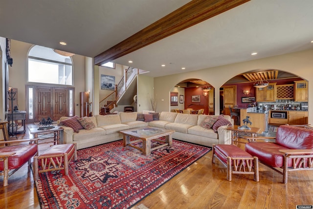 living area featuring light wood finished floors, beamed ceiling, stairway, and recessed lighting