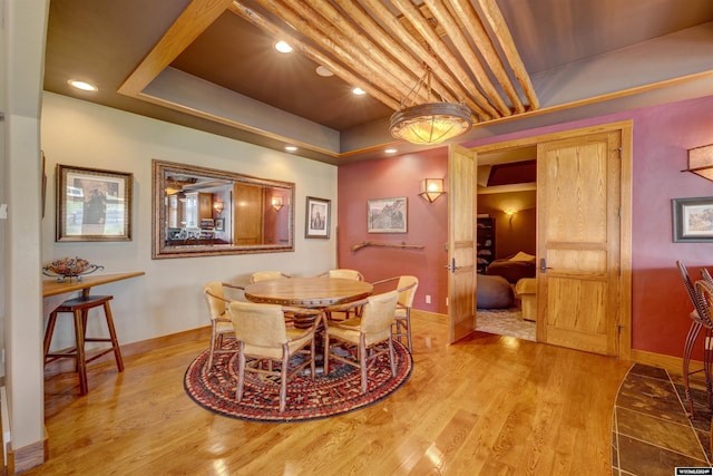 dining area featuring a tray ceiling, light wood-type flooring, recessed lighting, and baseboards