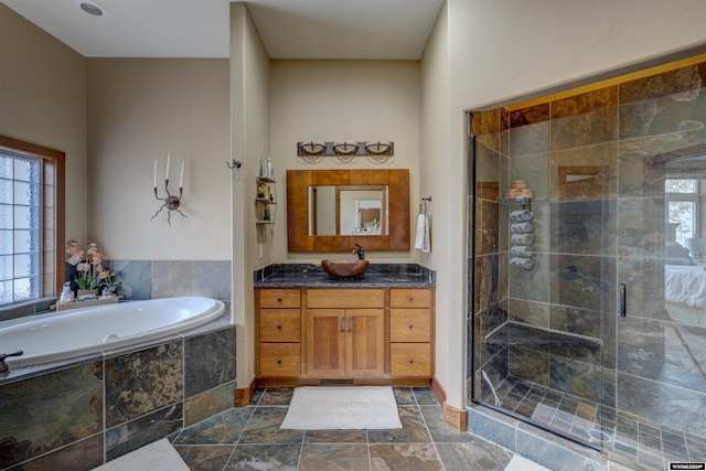 bathroom with stone finish flooring, a stall shower, vanity, and a bath