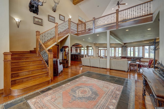 interior space featuring high vaulted ceiling, arched walkways, dark wood-style flooring, and stairway