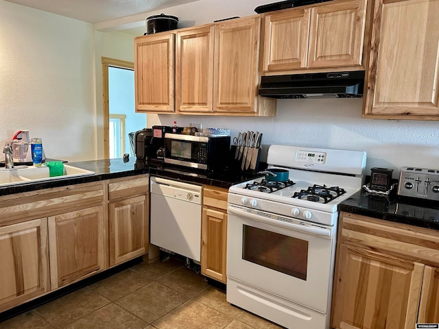 kitchen with dark tile patterned floors, light brown cabinetry, white appliances, and sink