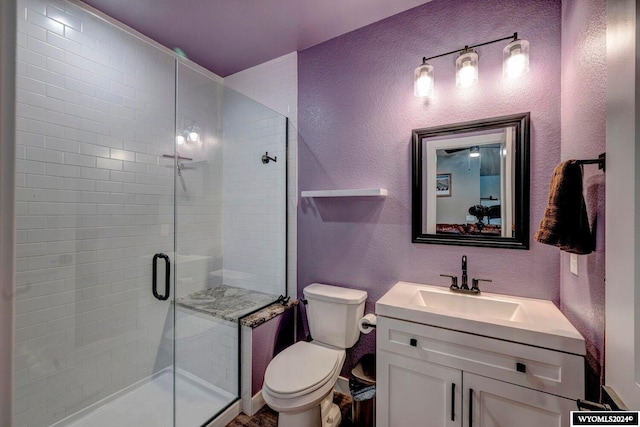 full bathroom with a stall shower, toilet, vanity, and a textured wall