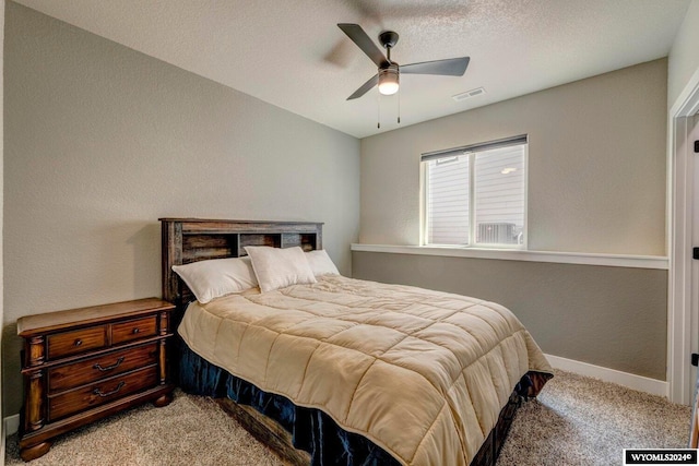 bedroom featuring a ceiling fan, visible vents, baseboards, a textured ceiling, and light colored carpet