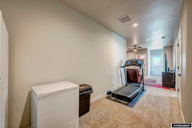 exercise room featuring baseboards, visible vents, carpet floors, and a textured ceiling