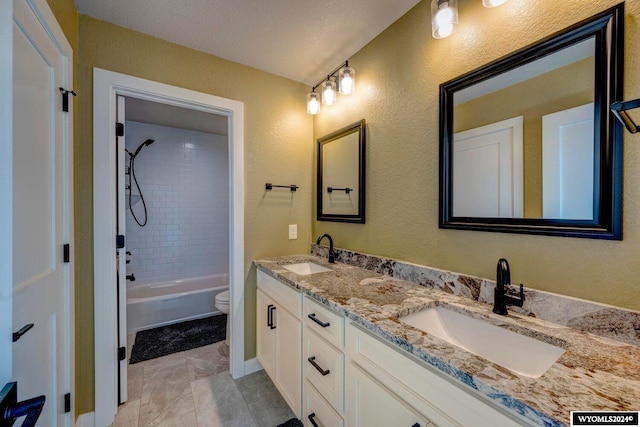 bathroom with a sink, shower / bathtub combination, toilet, and double vanity