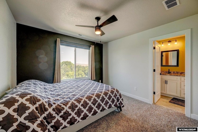 bedroom featuring a textured ceiling, baseboards, visible vents, and light carpet