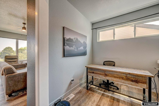 office area featuring plenty of natural light, wood finished floors, visible vents, and a textured ceiling