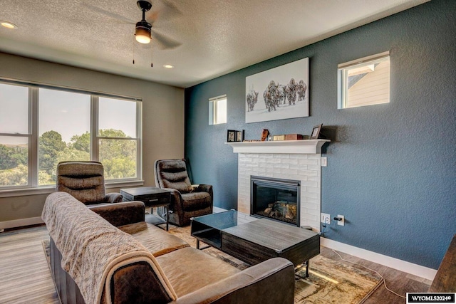 living room with baseboards, light wood-style flooring, a fireplace, and a textured wall