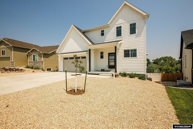 view of front of home featuring a garage, board and batten siding, driveway, and fence