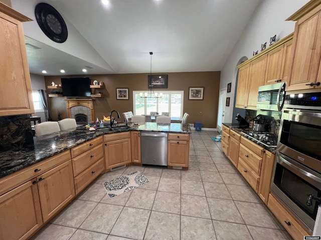 kitchen featuring appliances with stainless steel finishes, light tile patterned flooring, a tile fireplace, and sink