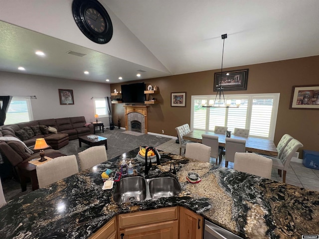 kitchen with carpet flooring, dark stone countertops, a notable chandelier, decorative light fixtures, and sink