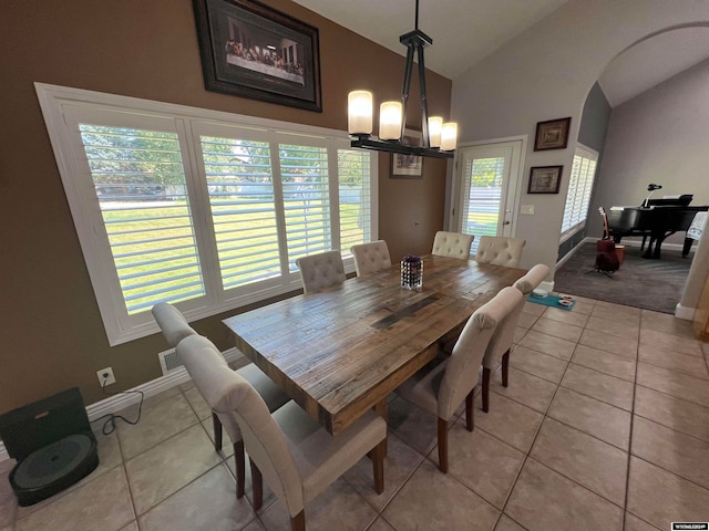 tiled dining area featuring a chandelier and lofted ceiling