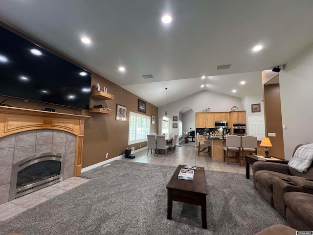 living room with a tiled fireplace, lofted ceiling, and light colored carpet