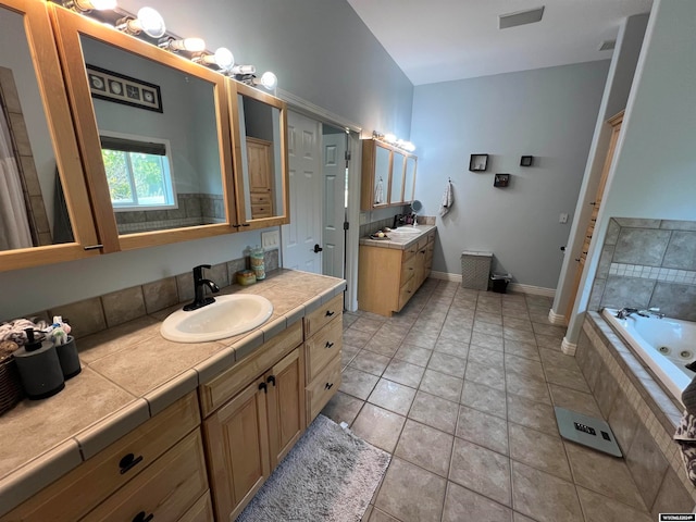 bathroom with vanity, tile patterned flooring, and tiled bath