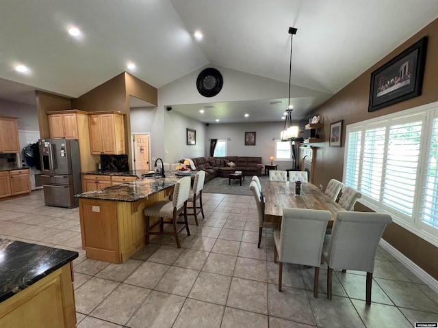 kitchen featuring stainless steel fridge, a breakfast bar, hanging light fixtures, decorative backsplash, and light tile patterned flooring