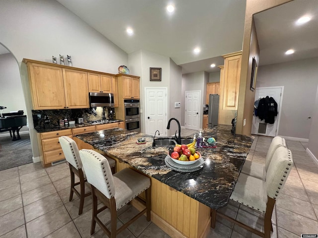 kitchen with a kitchen bar, appliances with stainless steel finishes, sink, light colored carpet, and high vaulted ceiling