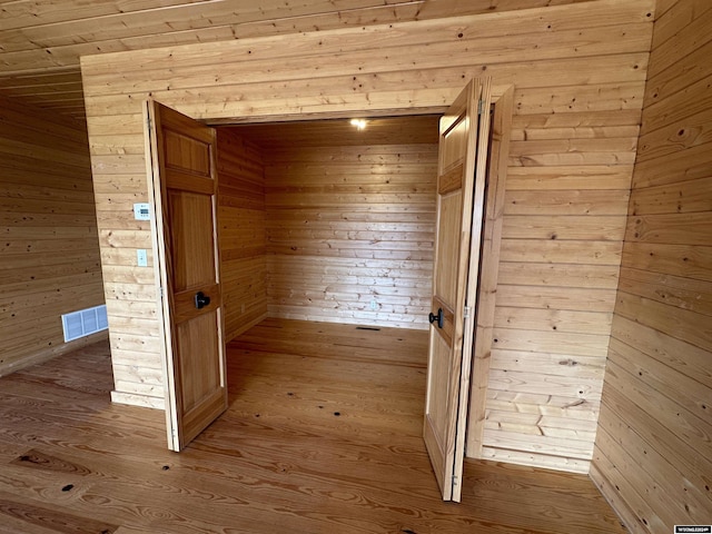 interior space featuring visible vents, wooden walls, and wood finished floors