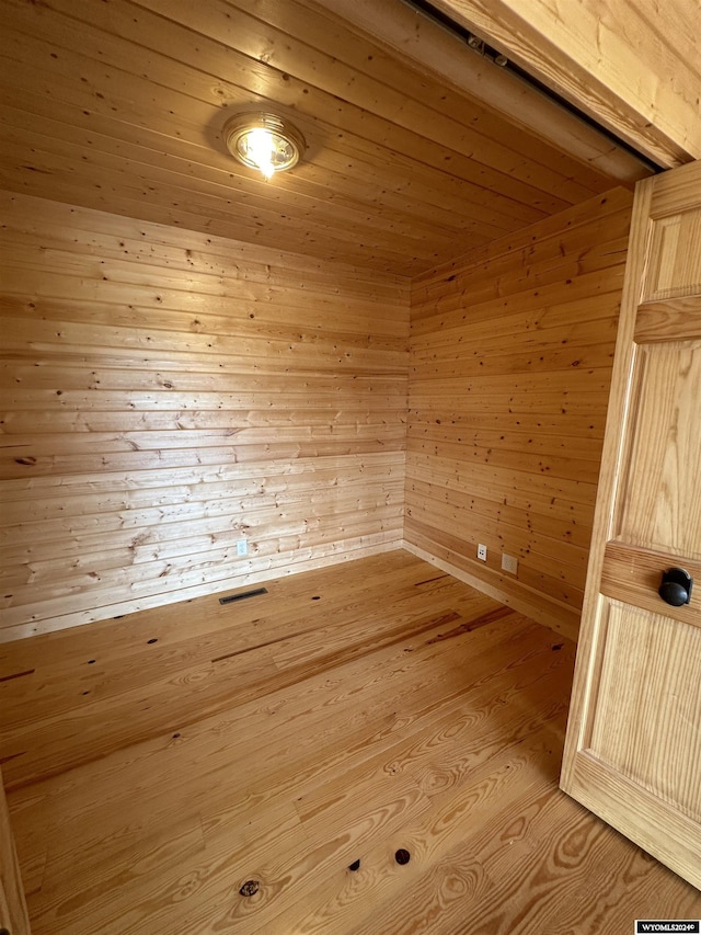 interior space with a sauna, wood walls, wood ceiling, and light wood-style floors