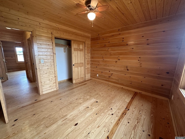 unfurnished bedroom featuring wooden walls, a closet, wooden ceiling, and light wood-style floors