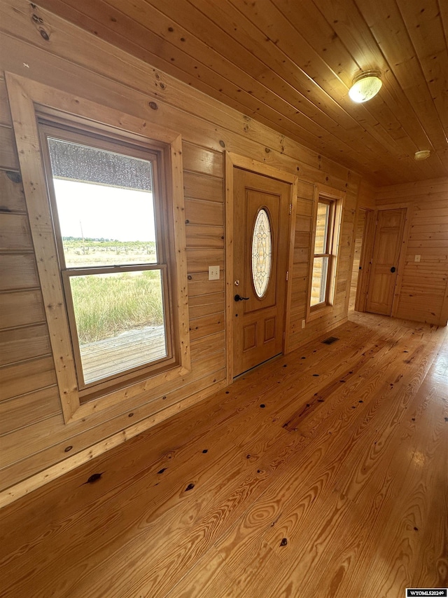 foyer featuring wooden ceiling, wooden walls, and light wood finished floors