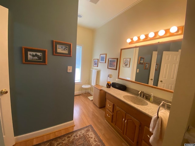 bathroom with vanity, toilet, wood-type flooring, and ornamental molding