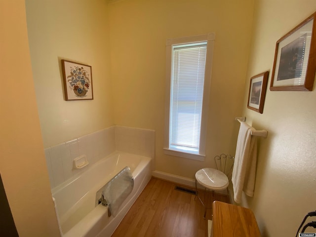 bathroom with a bath and hardwood / wood-style floors