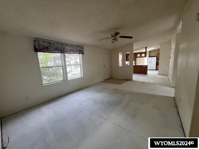 spare room with vaulted ceiling, ceiling fan, and a textured ceiling