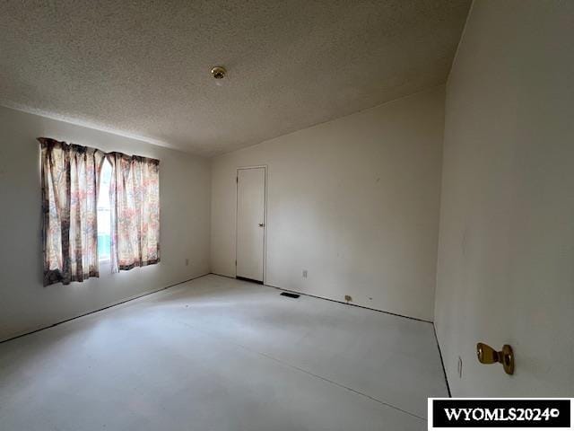 spare room featuring concrete flooring and a textured ceiling