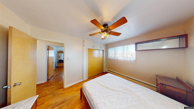 bedroom featuring a baseboard radiator, a closet, ceiling fan, and light wood-type flooring