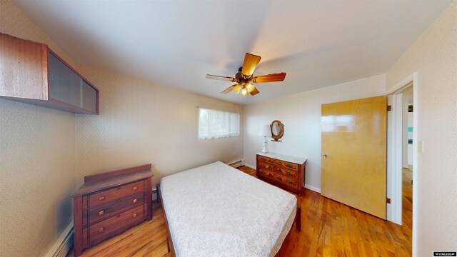 bedroom featuring light hardwood / wood-style floors, a baseboard radiator, and ceiling fan