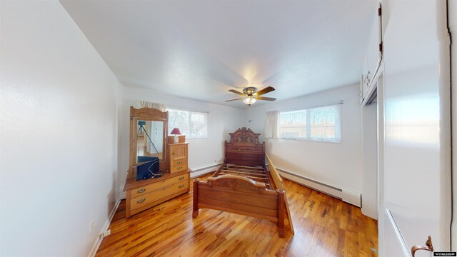 bedroom with a baseboard radiator, ceiling fan, and light hardwood / wood-style floors