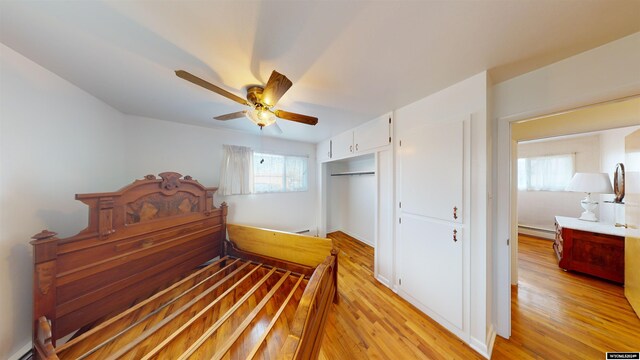 bedroom with a baseboard radiator, ceiling fan, light hardwood / wood-style flooring, and a closet