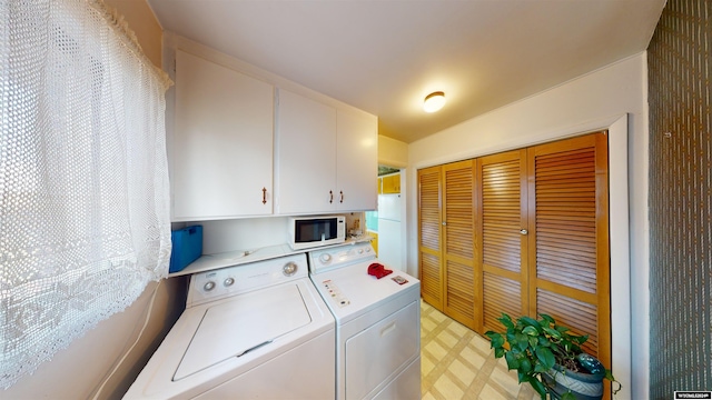 laundry area with washing machine and clothes dryer, cabinets, and light tile patterned floors