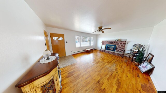 living room with a fireplace, hardwood / wood-style floors, a baseboard radiator, and ceiling fan