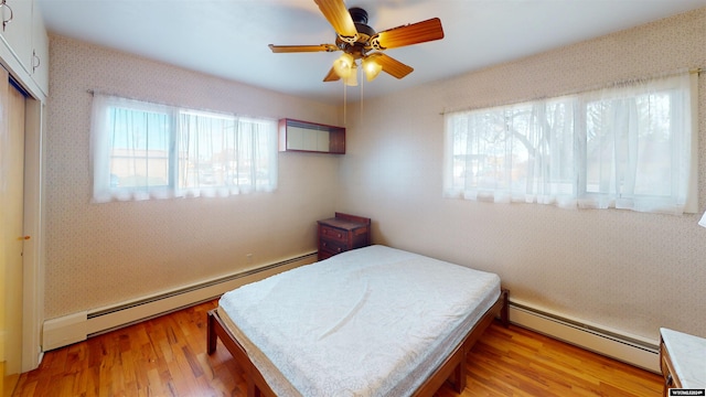 bedroom featuring a baseboard radiator, ceiling fan, light hardwood / wood-style flooring, and a closet