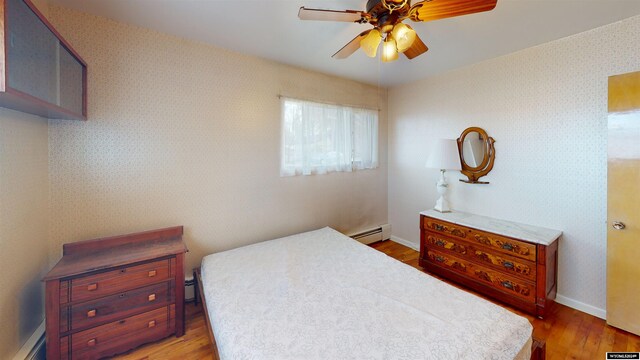 bedroom featuring baseboard heating, ceiling fan, and hardwood / wood-style floors