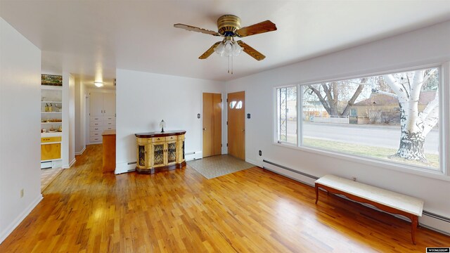 interior space featuring light hardwood / wood-style floors, a baseboard radiator, ceiling fan, and plenty of natural light