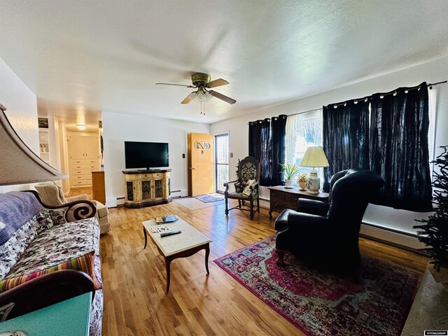 living room with ceiling fan, light wood-type flooring, and baseboard heating