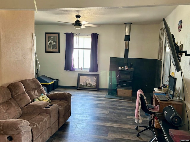 living room with a wood stove, wood-type flooring, and ceiling fan