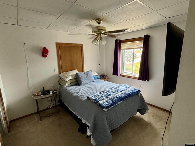 carpeted bedroom featuring ceiling fan and a drop ceiling