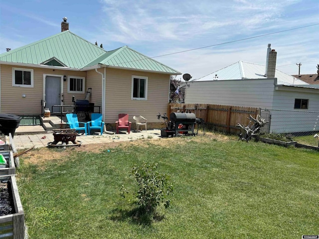 back of property with a patio, a lawn, and an outdoor fire pit