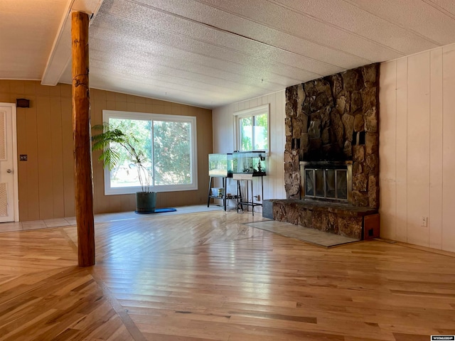 unfurnished living room featuring wood walls, light hardwood / wood-style flooring, and plenty of natural light