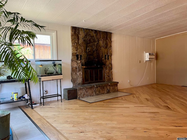 living room featuring a wall mounted air conditioner, a fireplace, a textured ceiling, and wood walls