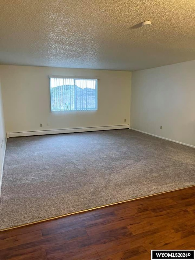 spare room featuring wood-type flooring, a textured ceiling, and baseboard heating